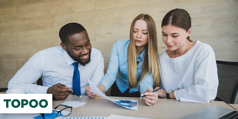 Três pessoas numa mesa analisando papéis com dados