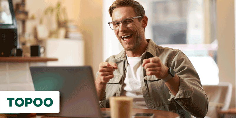 Homem feliz sentado em uma mesa com notebook