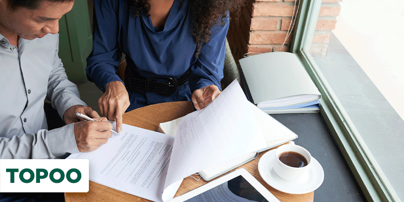 Homem e mulher sentados em mesa assinando documentos