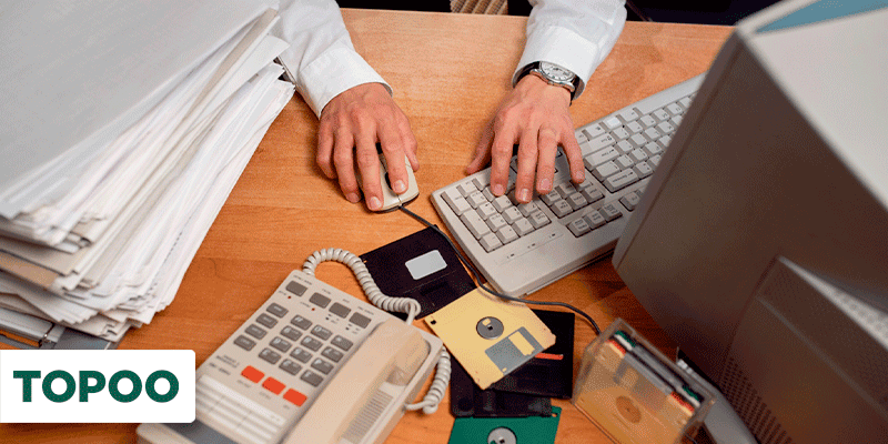 Homem em mesa de escritório com documentos, computador e telefone